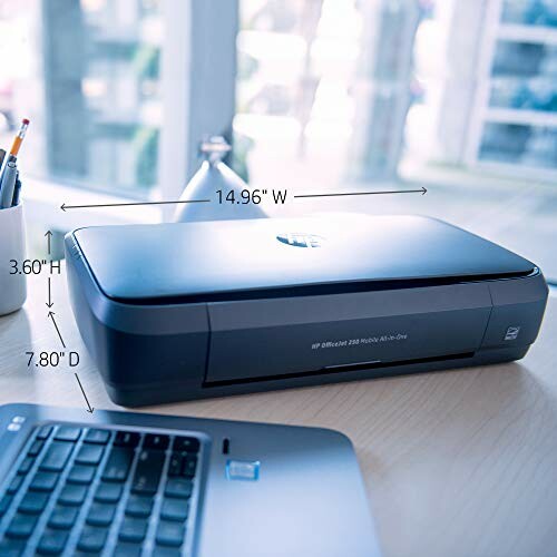 Compact printer on a desk beside a laptop.