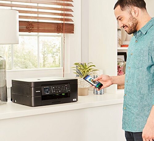 Man using a smartphone to operate a wireless printer on a white counter.