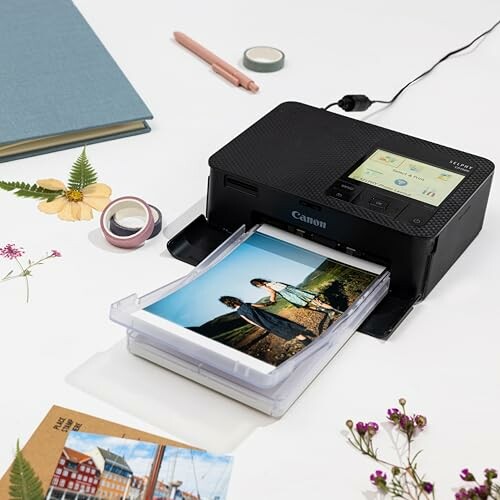 Portable photo printer printing an image on a desk with stationery items